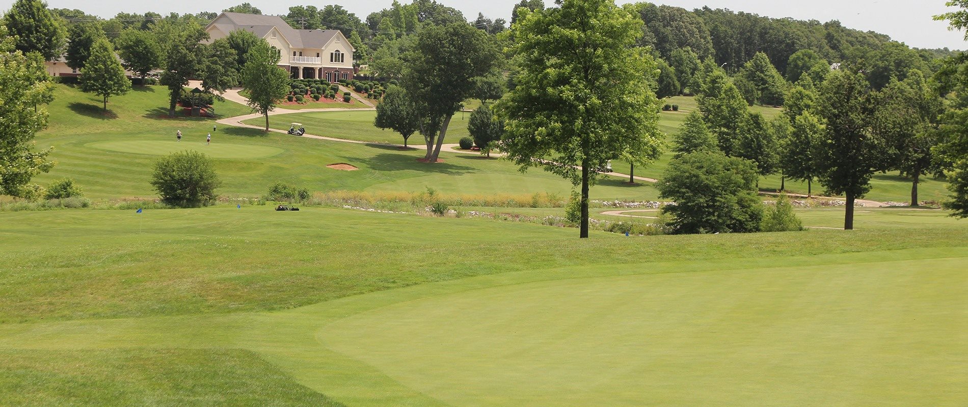 a golf course with a house in the background